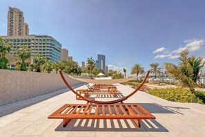 Une terrasse sur le toit, avec des chaises longues, des palmiers et une vue sur les toits de la ville en arrière-plan.