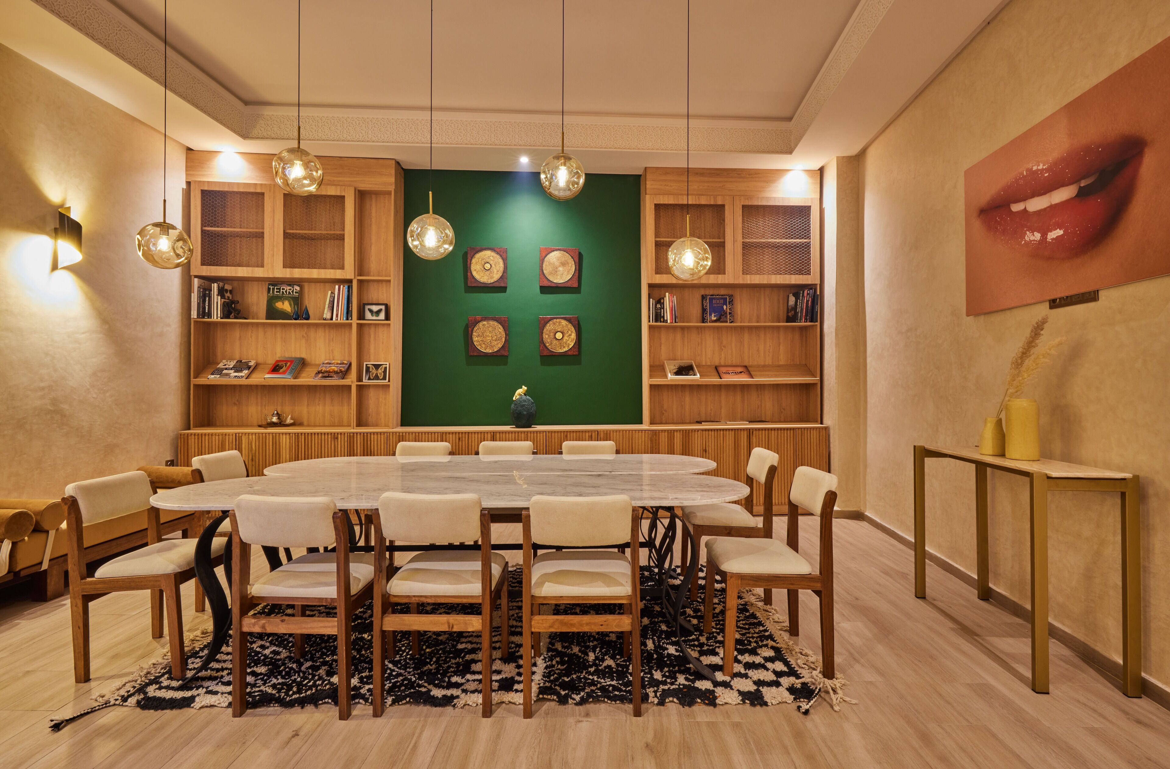 Un salón de conferencias con una mesa redonda, sillas, estanterías y decoración en la pared.