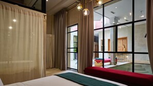 A hotel room with a large bed, a red bench, and a view of an outdoor area with a pool and a staircase. - ZEN ZONE BOUTIQUE RIAD (Marrakech)
