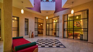 A spacious room with a checkered floor, a bed with green and red bedding, and large windows with curtains. - ZEN ZONE BOUTIQUE RIAD (Marrakech)