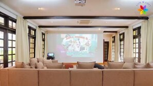 A spacious living room with a large sectional sofa, a flat-screen TV, and a projector screen displaying a presentation.