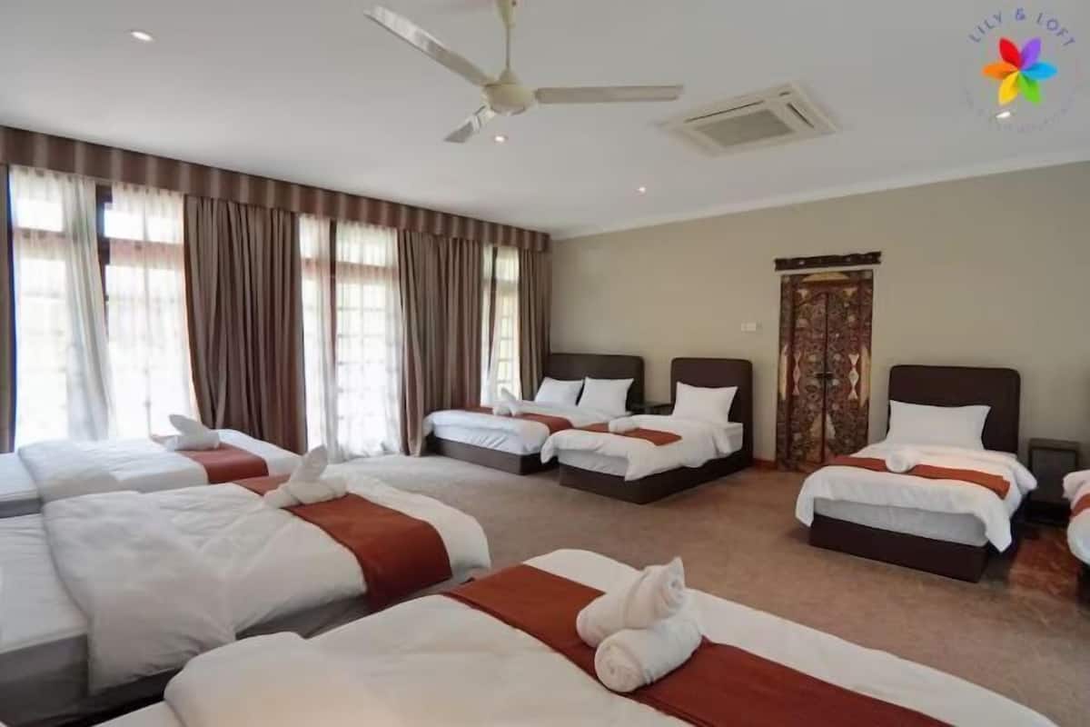 Une chambre d’hôtel avec quatre lits, un ventilateur de plafond et une grande fenêtre avec des rideaux.