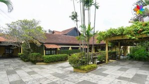 A courtyard with tiled flooring, potted plants, and a pergola.