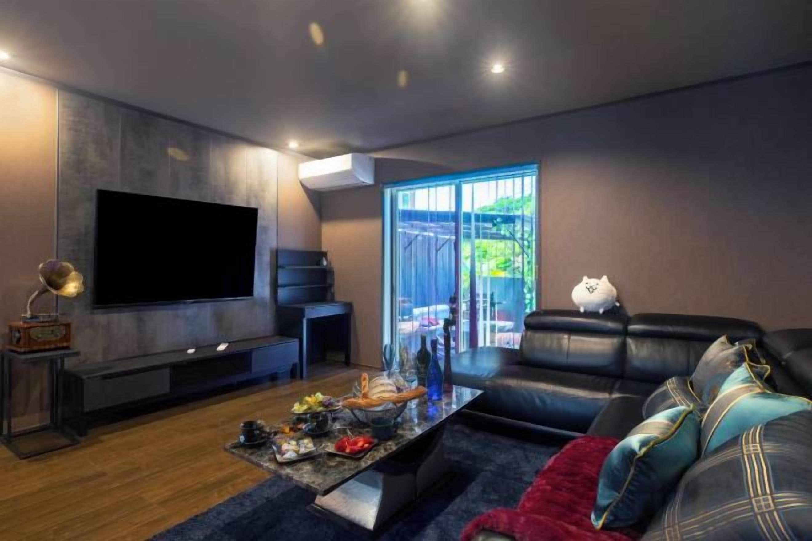 A modern living room with a flat-screen TV, a fireplace, a sofa, and a coffee table with various items.