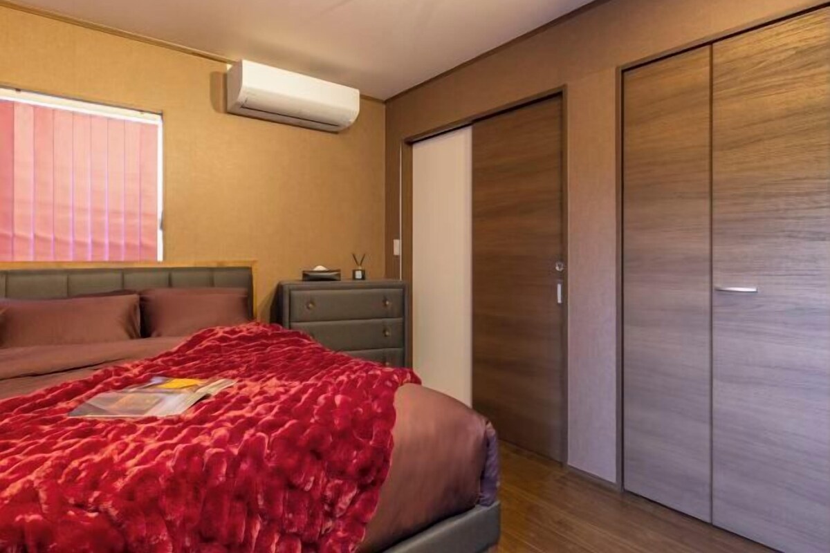 A bedroom with a bed, a dresser, a wardrobe, and a window with blinds.