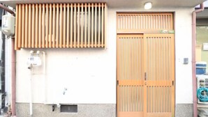 A building with a wooden door and a window with vertical blinds. - Ideal Momodani (Osaka)