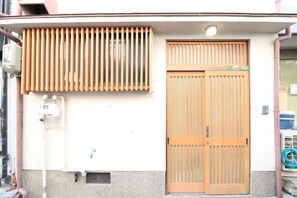 A building with a wooden door and a window with vertical blinds. - Ideal Momodani (Osaka)