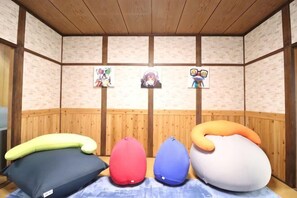 A room with wooden panel walls, a tatami mat floor, and a row of bean bags. - Ideal momodani (Osaka)