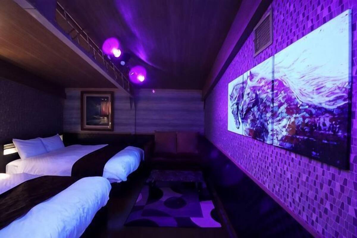 Habitació amb dos llits, un televisor fixat a la paret i una catifes amb dibuixos.