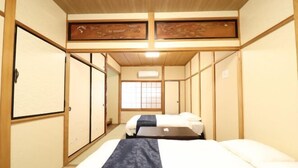 A traditional Japanese-style room with tatami flooring, a low ceiling, and sliding doors. - Ideal Momodani (Osaka)