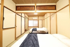 A traditional Japanese-style room with tatami flooring, a low ceiling, and sliding doors. - Ideal Momodani (Osaka)