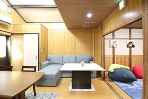 A room with a wooden ceiling, a sofa, a table, a bed, and a window with a view. - Ideal momodani (Osaka)