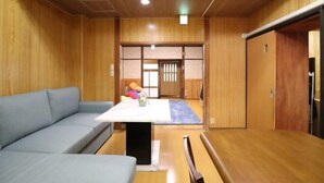 A room with a wooden floor, a sofa, a table with a white top, and a sliding door. - Ideal Momodani (Osaka)