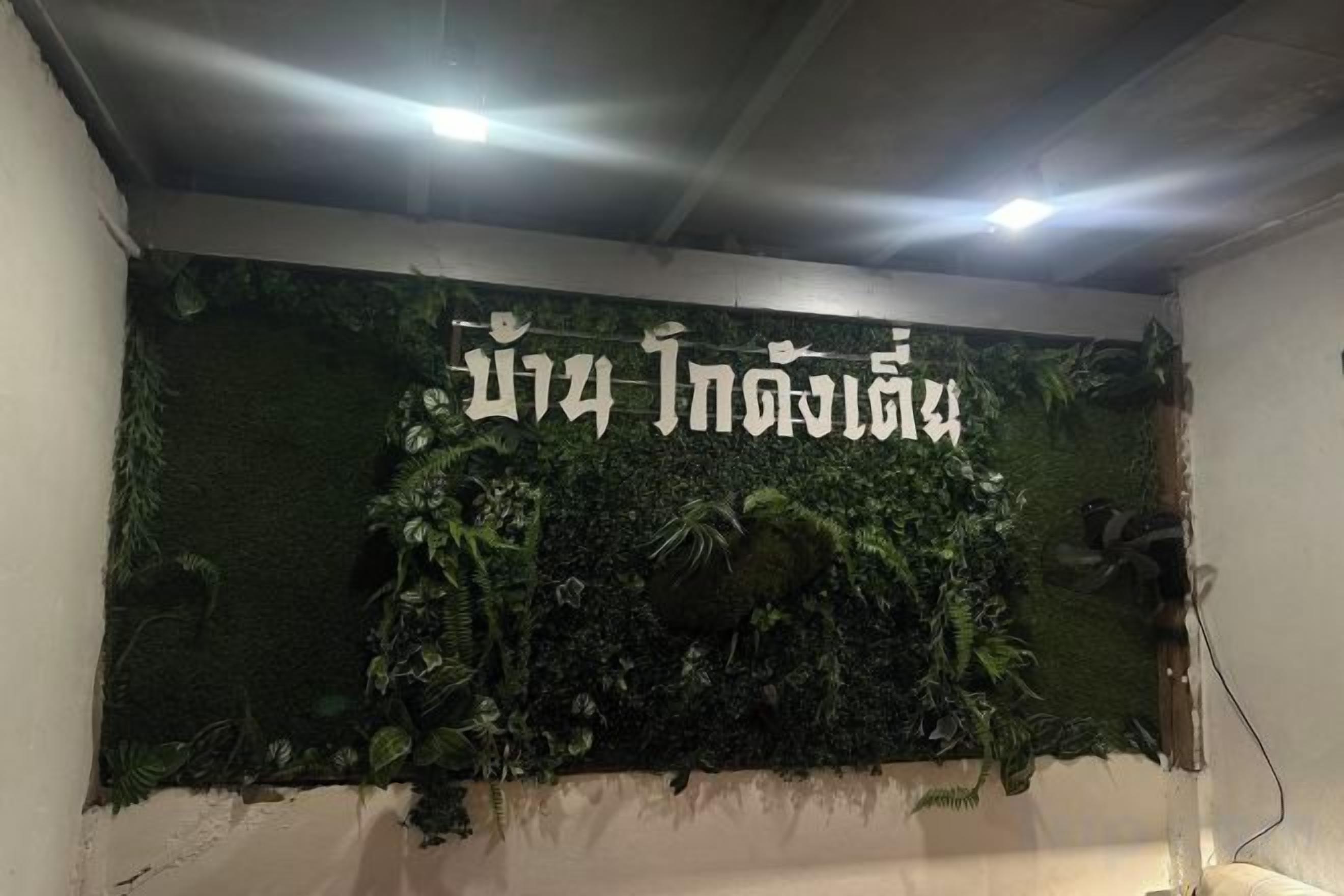 A wall with a green textured backdrop and white text, possibly a sign or nameplate.