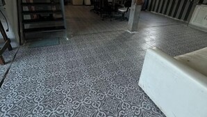 A room with patterned floor tiles, a white sofa, and a dining area with chairs and a table. - BanGoDangtia (Pak Chong)