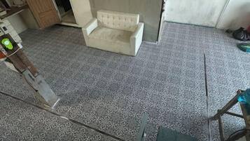 Quarto com piso estampado, um sofá branco e uma poltrona.