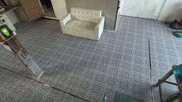 Quarto com ladrilhos no chão, sofá branco e escada de madeira.