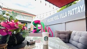 Une table en verre avec une tasse Starbucks, un canapé et un panneau indiquant : « Bienvenue à la villa avec piscine de Pattaya ».