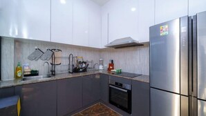 Une cuisine moderne avec des meubles gris, un réfrigérateur en acier inoxydable et un four encastré.