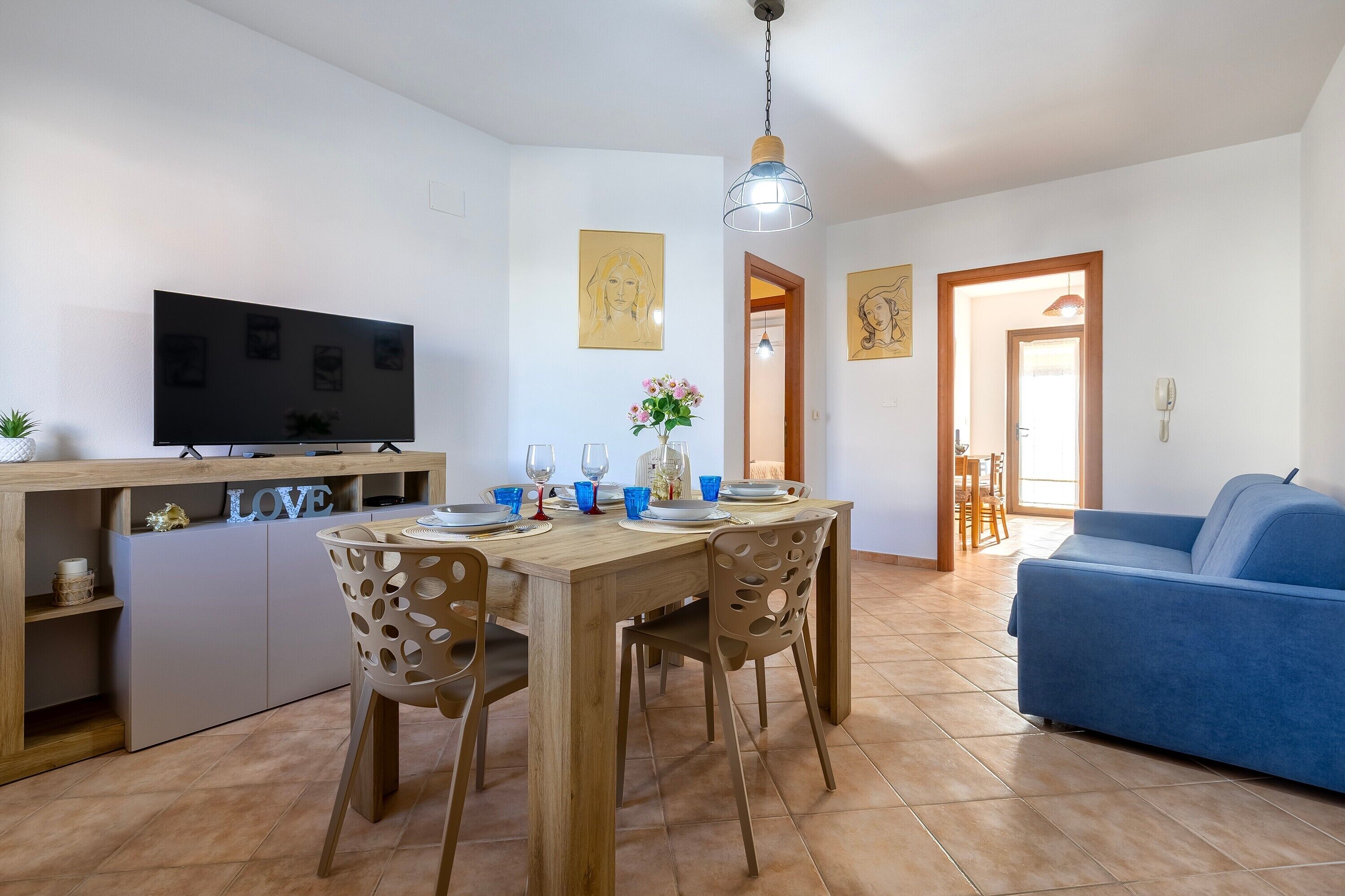Un salon moderne comprenant un téléviseur, une table à manger, des chaises et un canapé.