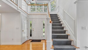 Un magnifique escalier, agrémenté d’un tapis à motifs, avec des murs blancs et un plancher en bois.