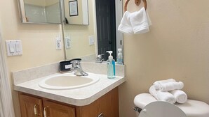 Une salle de bain équipée d’un lavabo, d’un miroir, de toilettes et d’un porte-serviettes.