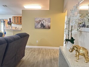 A living room with a sofa, a painting of a horse, and a decorative elephant on a console table.