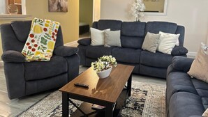 Un salon avec deux canapés sombres, une table basse en bois et un plaid à motifs.