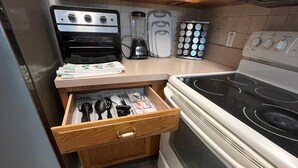 Une cuisine équipée d’un four Curtis Stone, d’un mixeur, d’une machine à café et d’un étagère à épices.
