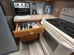 A kitchen with a Curtis Stone oven, a blender, a coffee maker, and a spice rack.