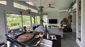 Uma cozinha moderna com uma ilha grande, uma área de jantar com sofá e uma TV fixada na parede.