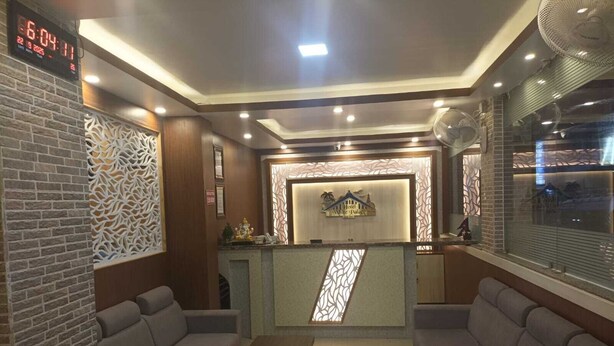 A hotel reception area with a reception desk, two sofas, a coffee table, and a digital clock displaying the time. - Hotel white palace airport Kathmandu  (Kathmandu)