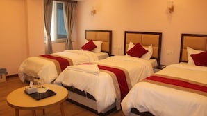 A hotel room with three beds, each with white bedding and red accents, a small round table with amenities, and a window with curtains. - Hotel white palace airport Kathmandu  (Kathmandu)