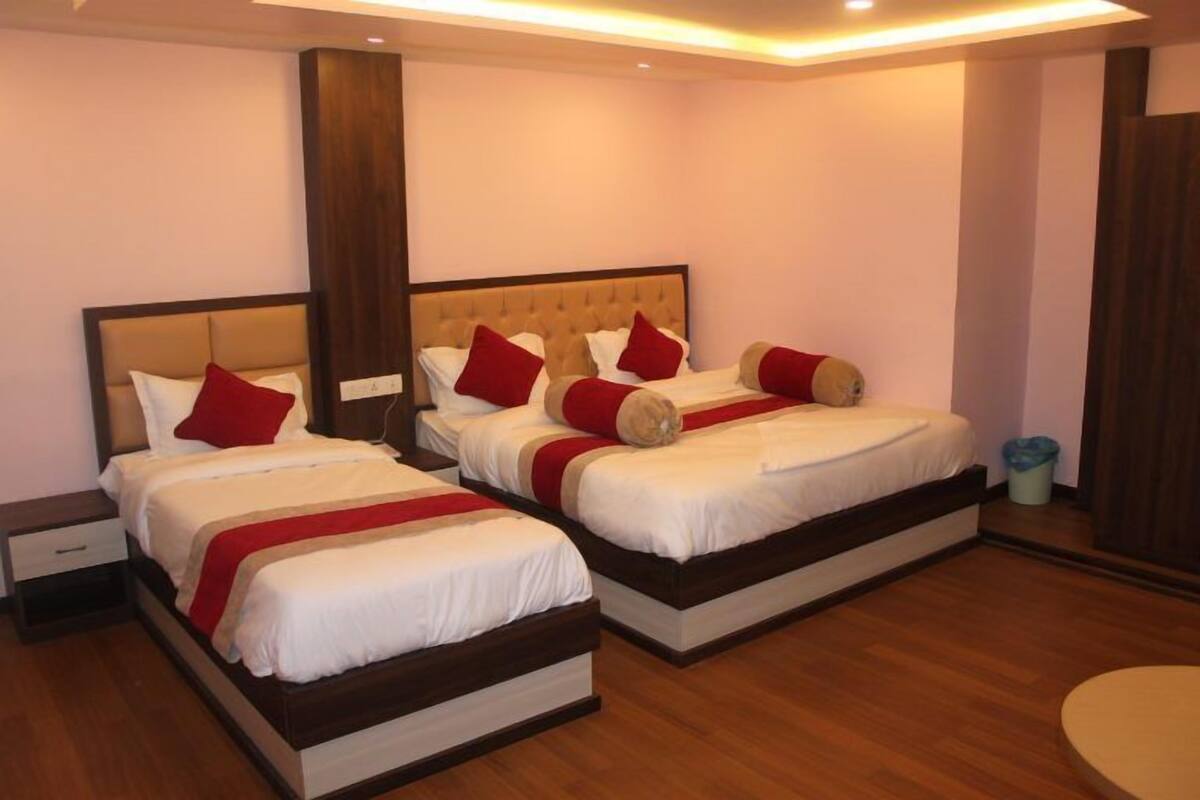 Une chambre d’hôtel avec deux lits, chacun doté d’une tête de lit en bois, de draps blancs et d’oreillers rouges.