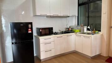 A compact kitchen with a black refrigerator, a microwave, a gas stove, and white cabinets.