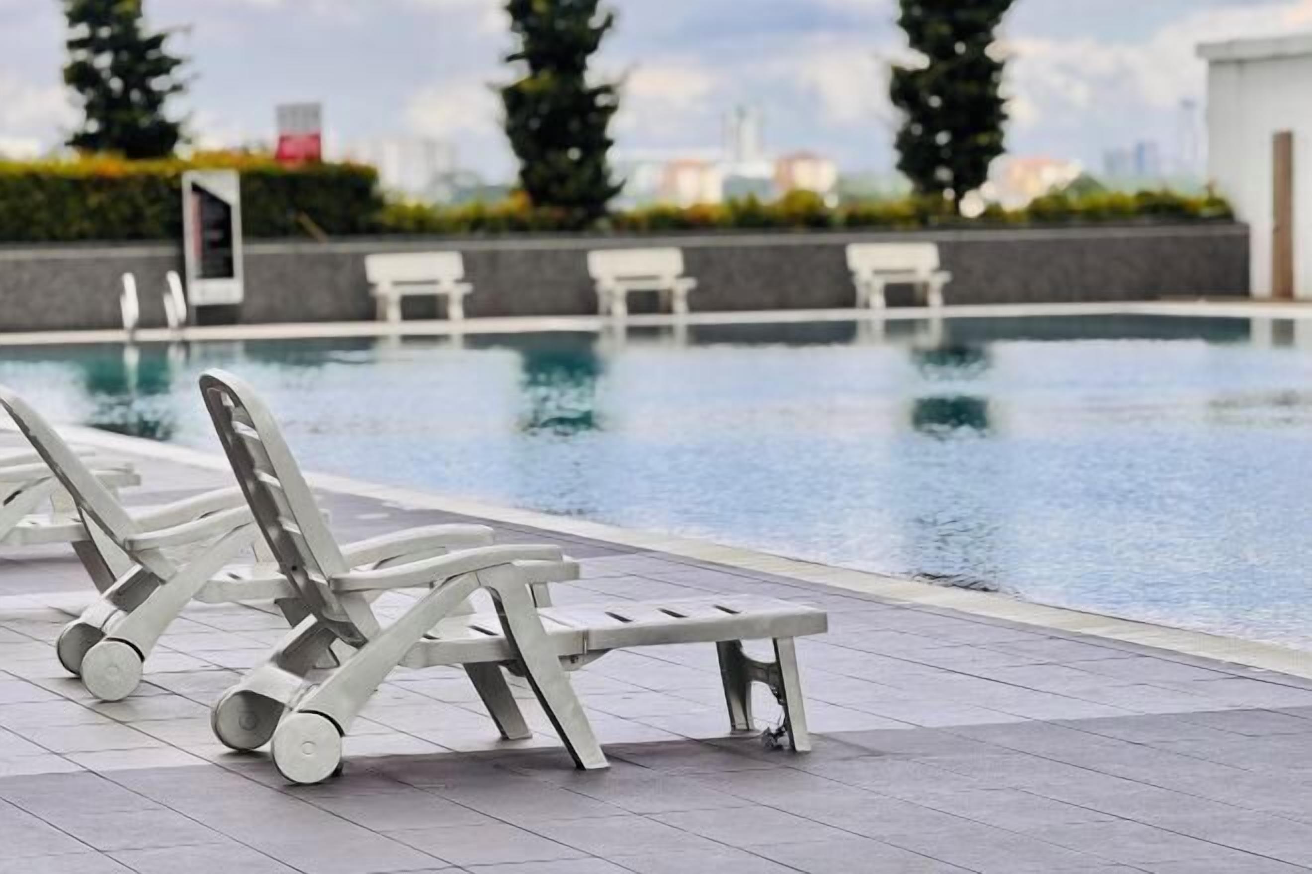A swimming pool with lounge chairs and a tiled deck.