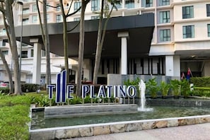 A hotel entrance with a sign reading 'The Platino,' a water feature, and a modern building facade.