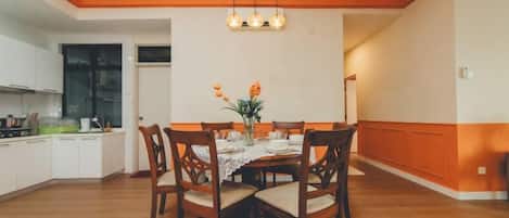 Un espace repas comprenant une table en bois, des chaises et un luminaire suspendu.