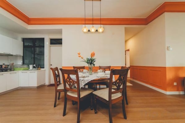 A dining area with a wooden table, chairs, and a hanging light fixture.