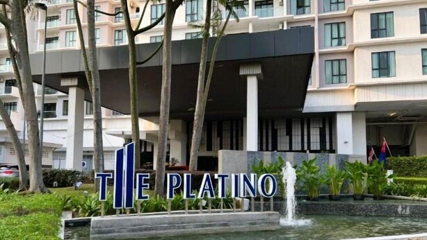 Entrada de hotel con un letrero que dice "THE PLATINO" y una fuente en primer plano.