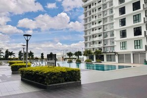 A modern hotel with a swimming pool, landscaped garden, and a multi-story building.