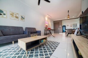 A modern living room with a grey sofa, a wooden coffee table, and a patterned rug. There is a neon sign on the wall and a ceiling fan. - The Platino Johor Bahru (Tebrau)