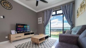 A modern living room with a large TV, a wooden coffee table, and a grey sofa. - The Platino Johor Bahru (Tebrau)