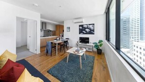 A modern apartment with a dining area, kitchen, and a large window offering a city view. - A Chic 2BR Apt, City Views Near Southern Cross (Melbourne)