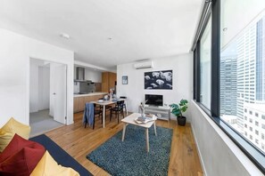 A modern apartment with a dining area, kitchen, and a large window offering a city view. - A Chic 2BR Apt, City Views Near Southern Cross (Melbourne)