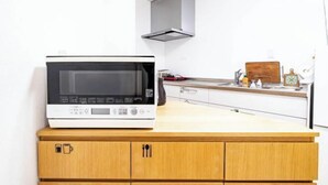 Cocina con microondas sobre una encimera de madera, pared blanca y campana extractora de acero inoxidable.