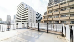 Un edificio moderno con varios pisos y balcones, que presenta un techo plano y un suelo reflectante.