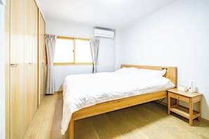 Une chambre à coucher avec un lit en bois, une table de chevet, une armoire et une fenêtre avec des rideaux.