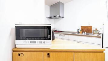 A kitchen with a microwave on a wooden counter, a stainless steel sink, and a white cabinet.