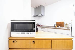 A kitchen with a microwave on a wooden counter, a stainless steel sink, and a white cabinet. - Torikari 5-chome1-10 (Fukuoka)